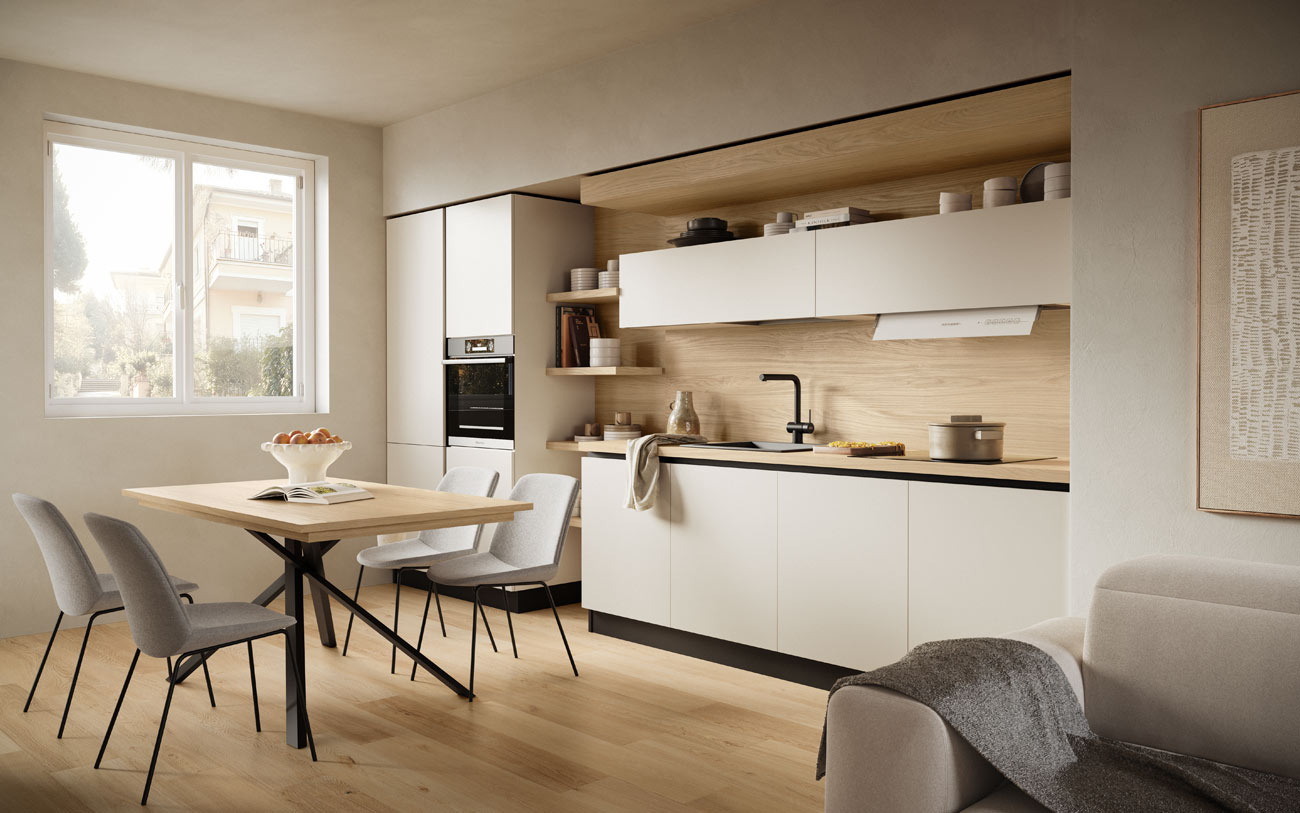 Tavolo Noa con con struttura in metallo nero e piano in Noce biondo con cucina lineare sullo sfondo