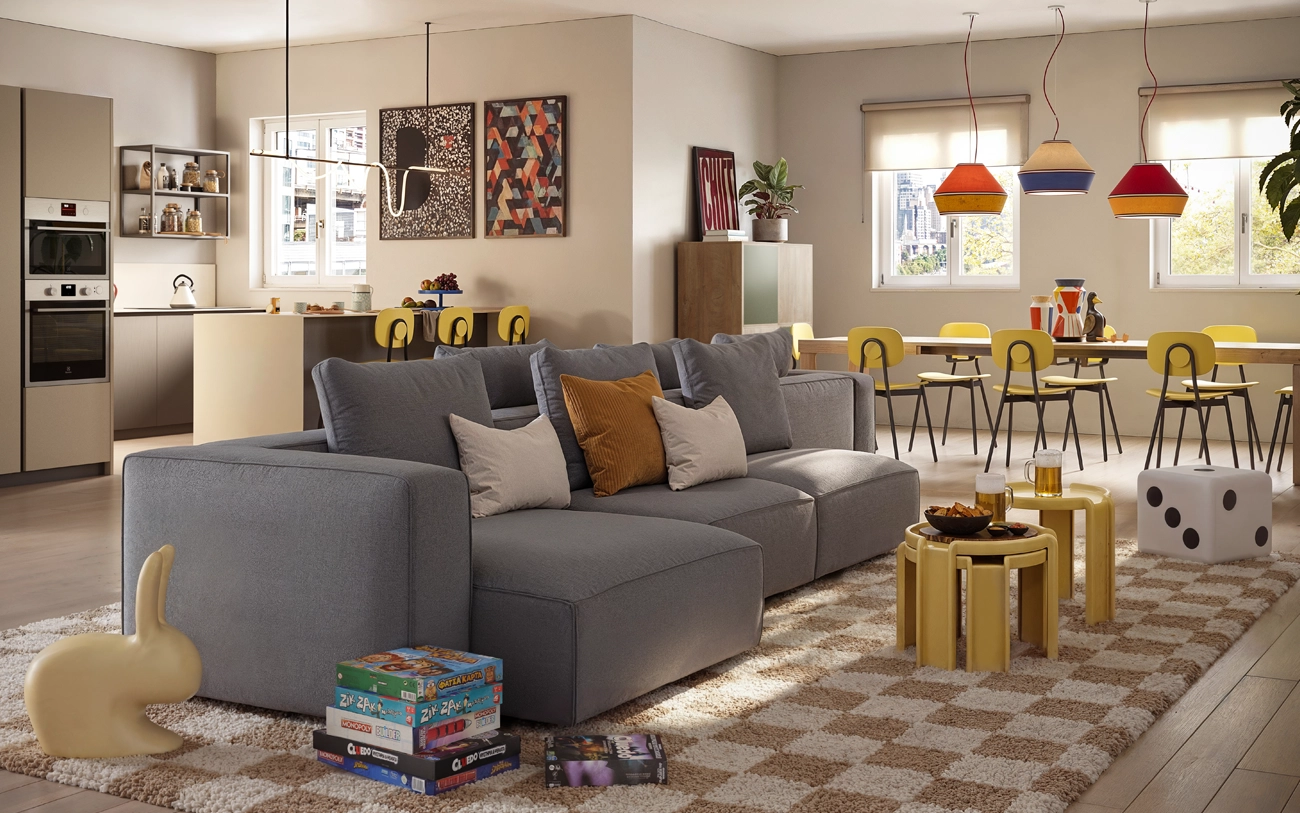 Soggiorno con divano componibile in tessuto grigio e cucina sullo fondo